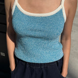 Person wearing a blue tank top with white trim on a street background