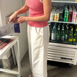Person in a red and white striped top and white pants standing in front of a cooler with drinks.