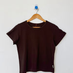 Brown t-shirt on a wooden hanger against a white wall