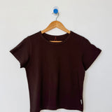 Brown t-shirt on a wooden hanger against a white wall