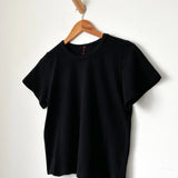 Black t-shirt on a wooden hanger against a white background