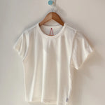 White t-shirt on a wooden hanger against a white wall