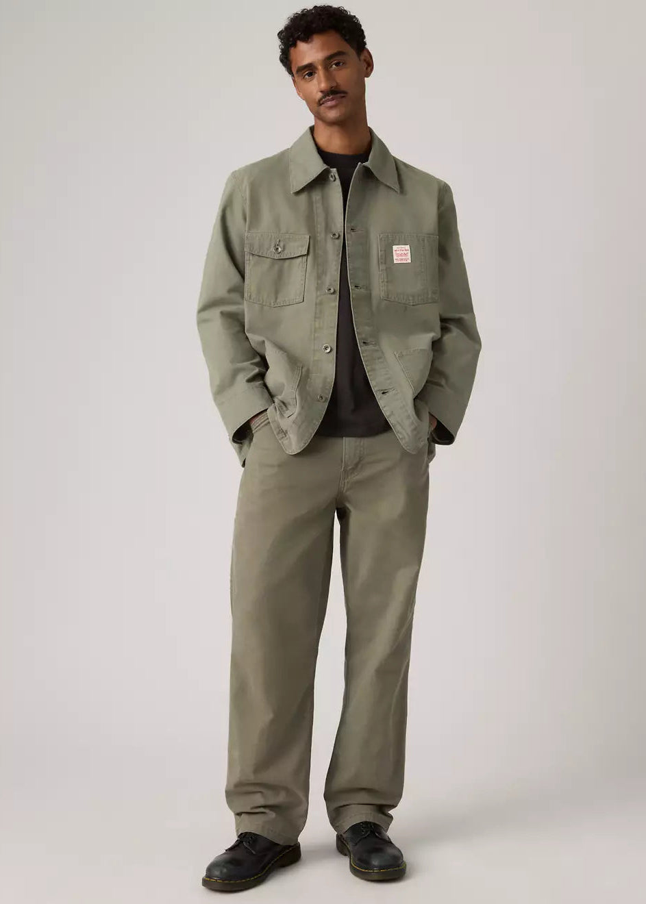 Man wearing a green jacket and pants on a plain background