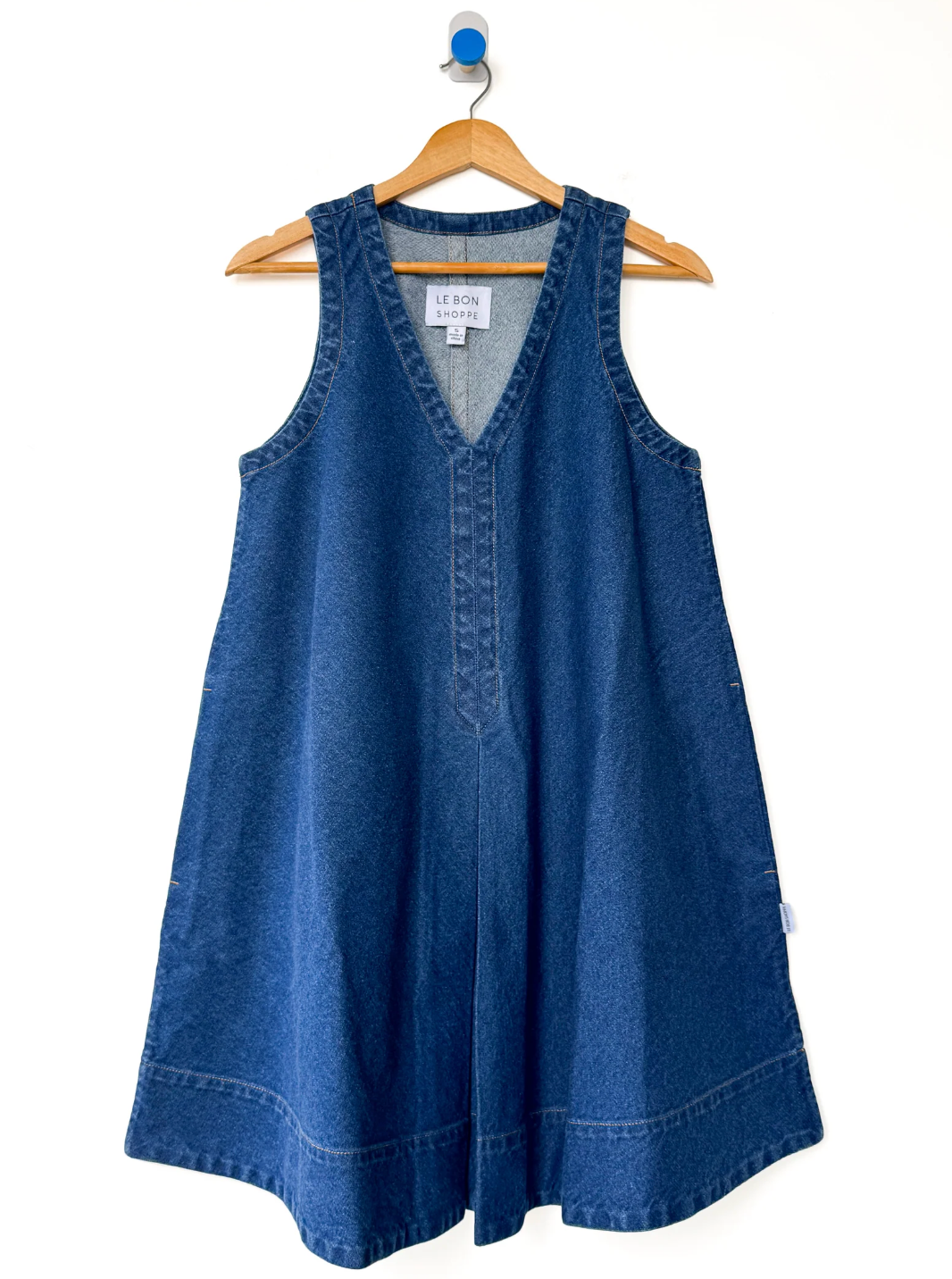 Blue denim dress on a hanger against a white background