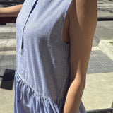 Person wearing a blue and white striped dress on a city street.