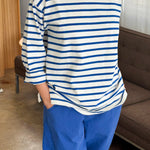 Person wearing a blue and white striped shirt with blue pants in an indoor setting.