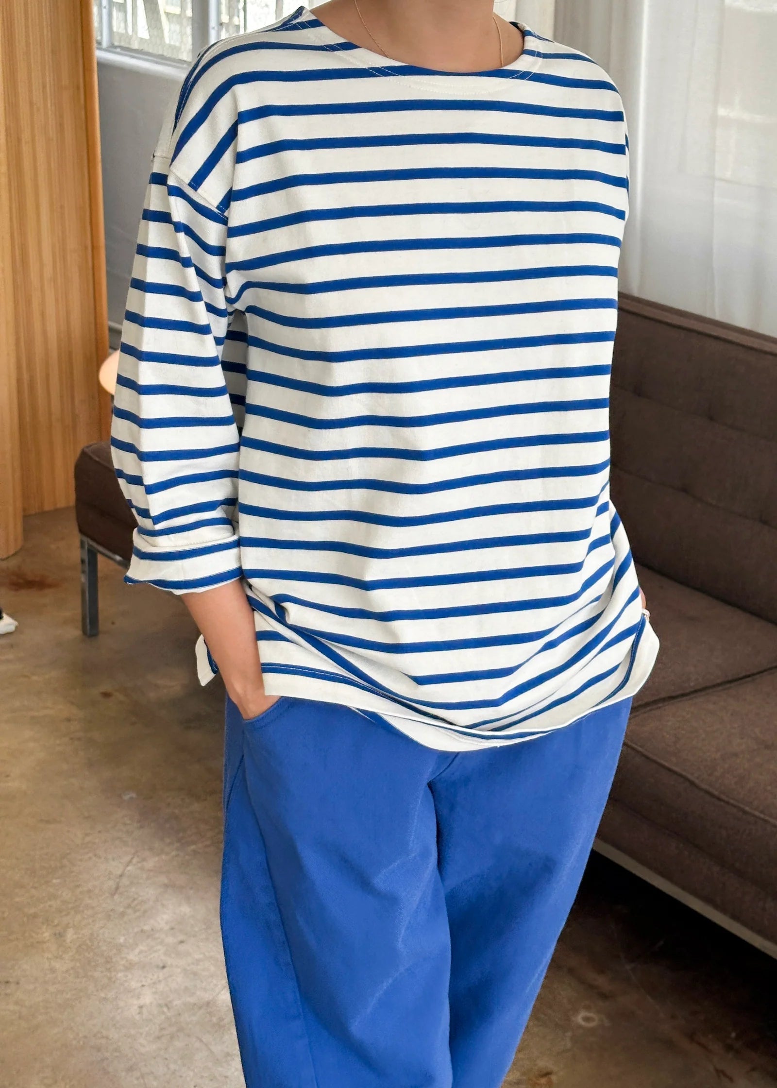 Person wearing a blue and white striped shirt with blue pants in an indoor setting.