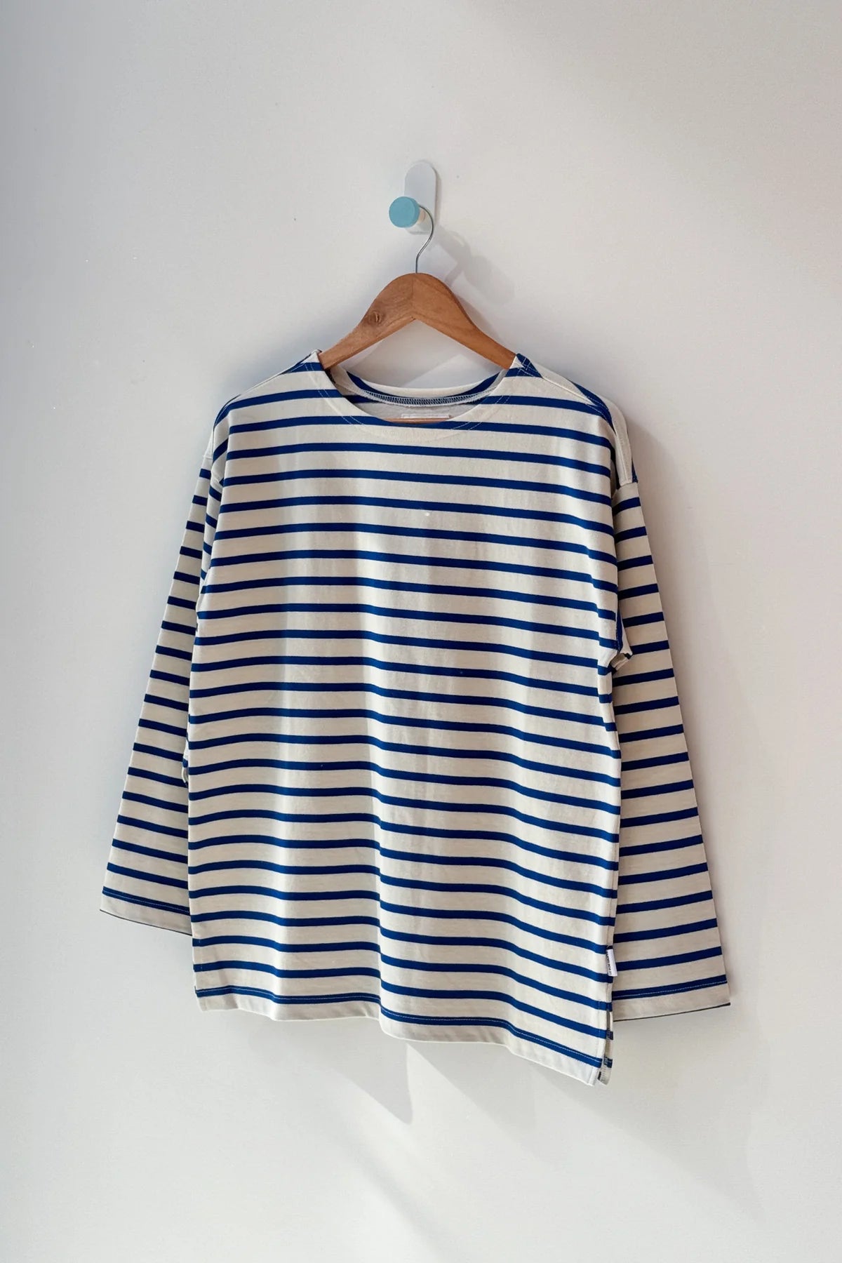 Blue and white striped shirt on a wooden hanger against a white background
