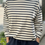 Person wearing a navy and white striped shirt with navy pants outdoors.