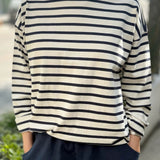 Person wearing a navy and white striped shirt with navy pants outdoors.