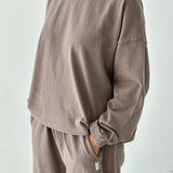 Person wearing a brown sweatshirt and pants set against a white background