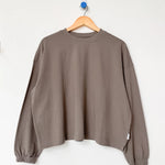 Brown sweater on a wooden hanger against a white background