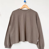 Brown sweater on a wooden hanger against a white background