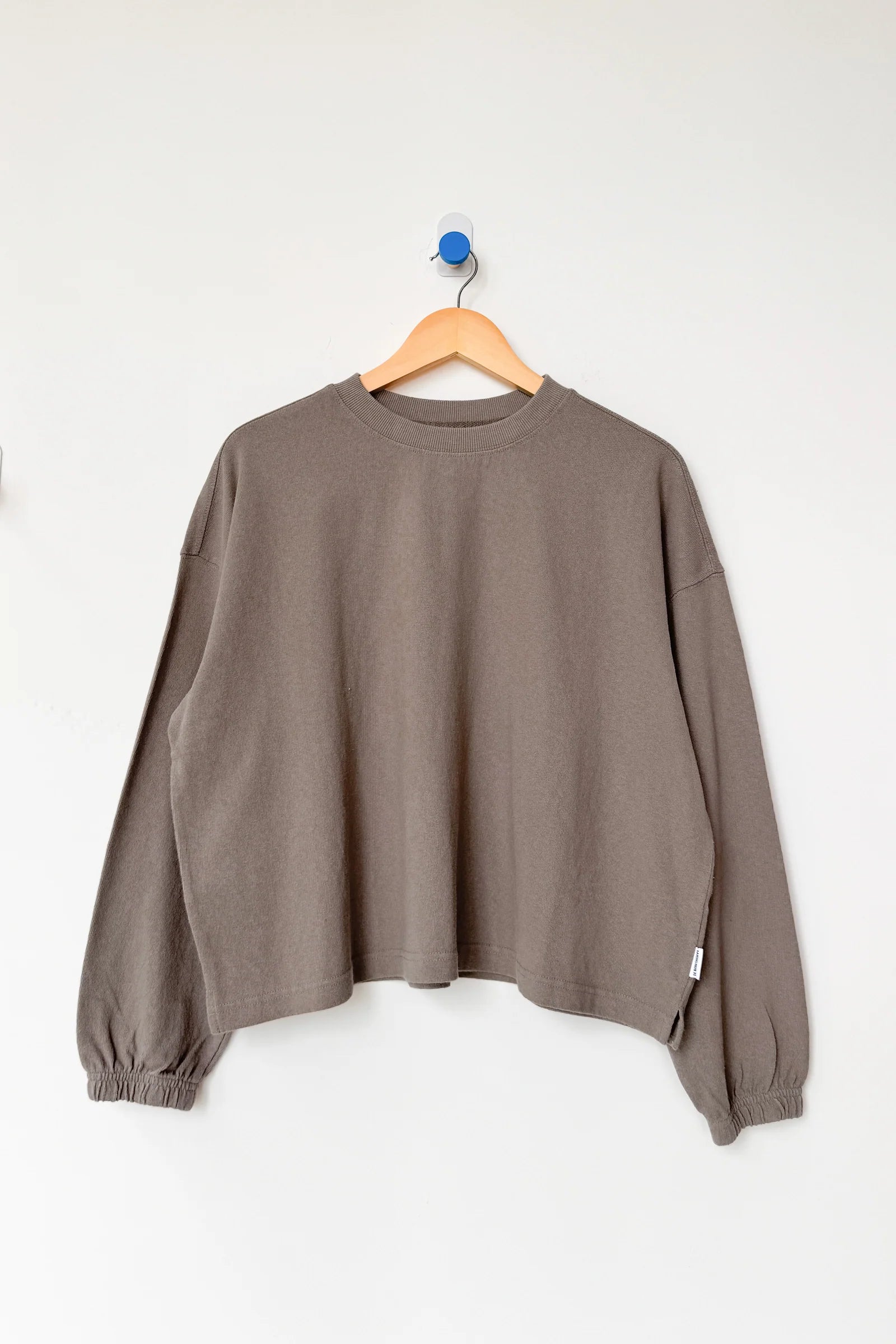 Brown sweater on a wooden hanger against a white background