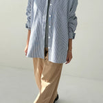 Person wearing a blue checkered shirt and beige pants on a white background