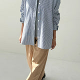 Person wearing a blue checkered shirt and beige pants on a white background