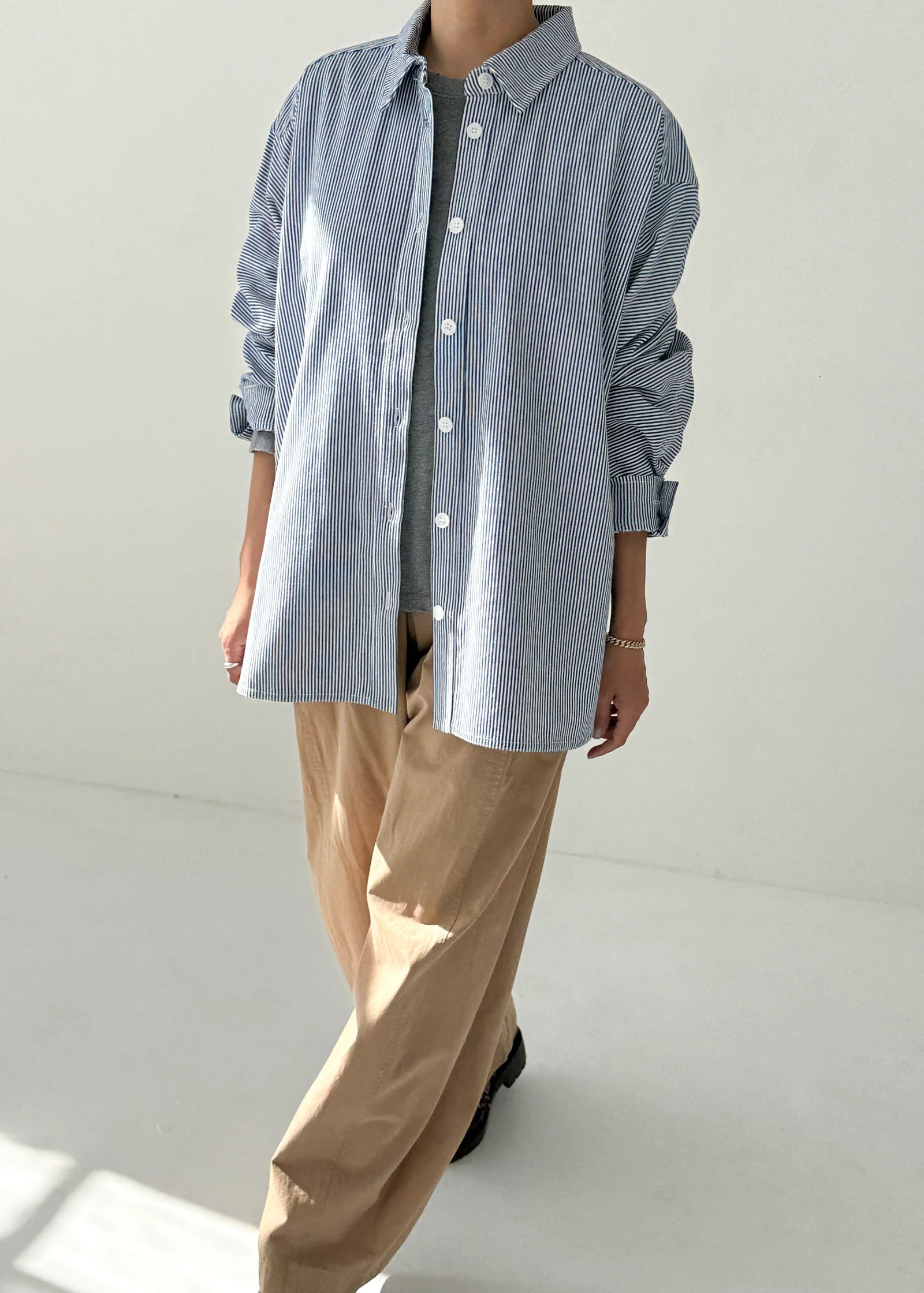 Person wearing a blue checkered shirt and beige pants on a white background