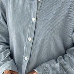 Close-up of a person wearing a blue and white striped shirt with rolled-up sleeves.