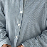 Close-up of a person wearing a blue and white striped shirt with rolled-up sleeves.