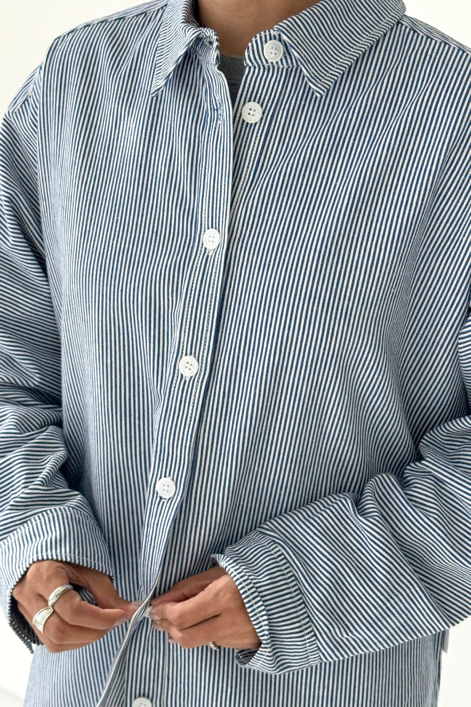 Close-up of a person wearing a blue and white striped shirt with rolled-up sleeves.