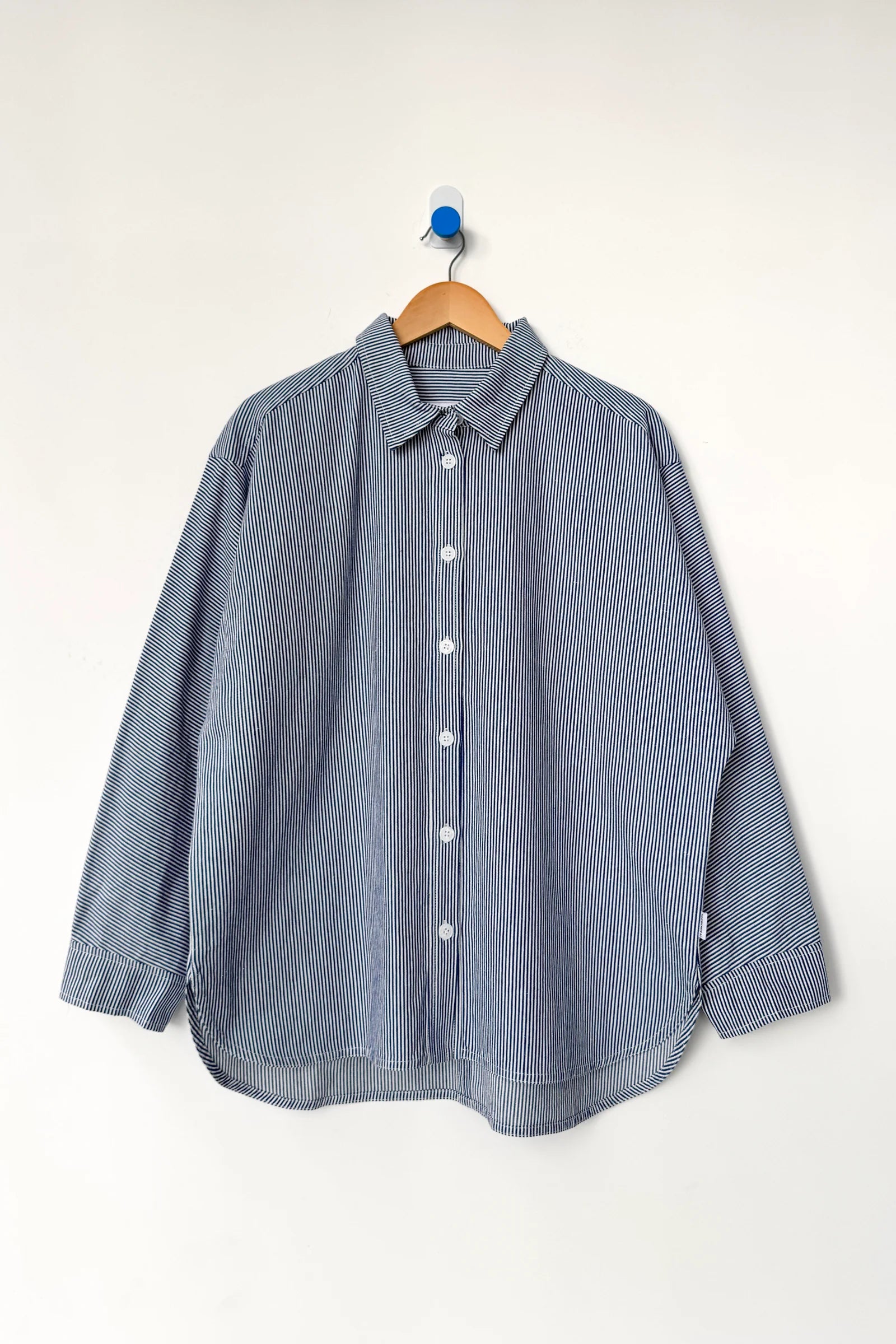 Blue striped shirt on a wooden hanger against a white background
