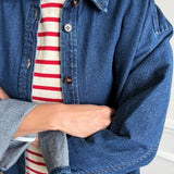 Person wearing a red and white stripe tee with an open denim shirt over it.