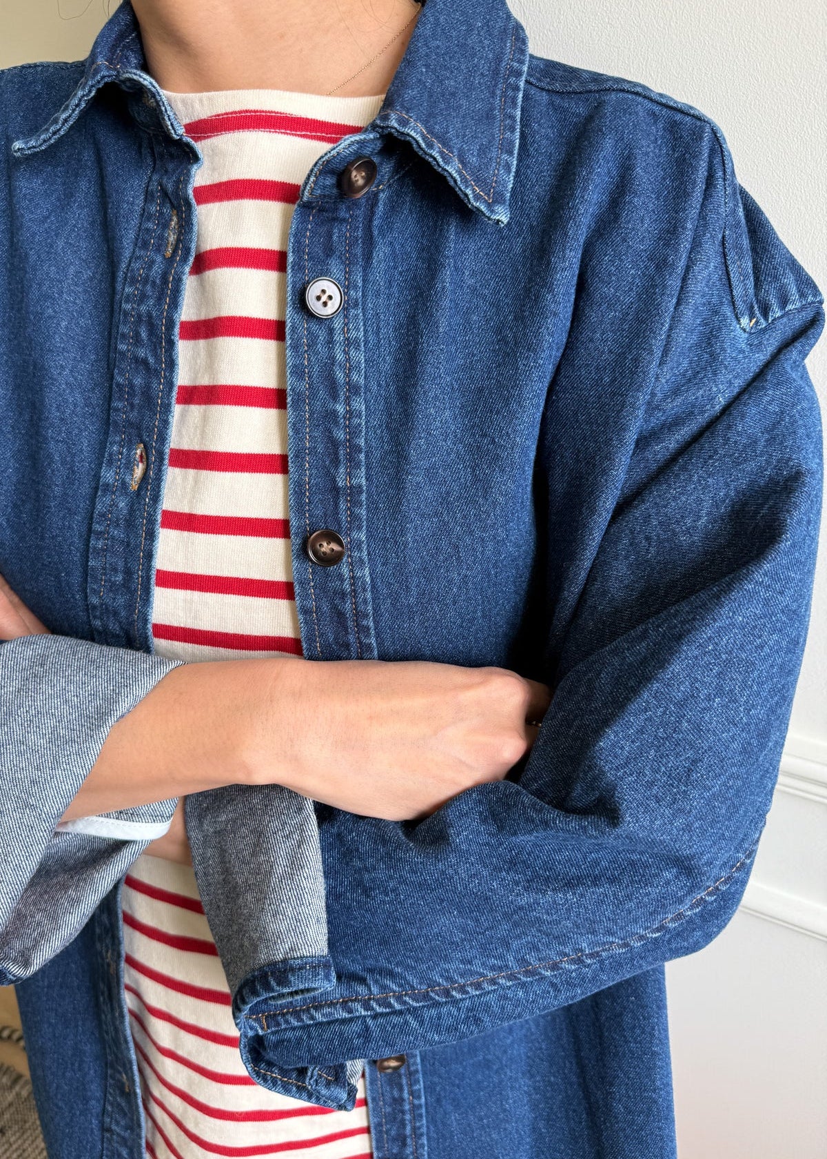 Person wearing a red and white stripe tee with an open denim shirt over it.