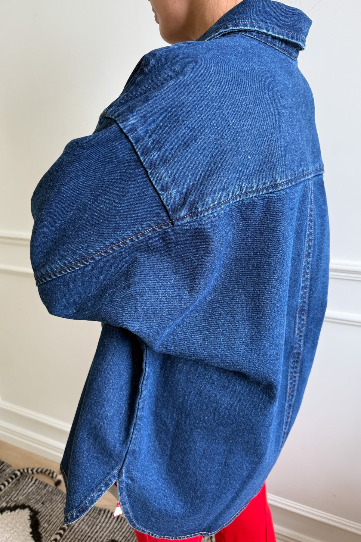 Back of person wearing a dark denim shirt and red pants