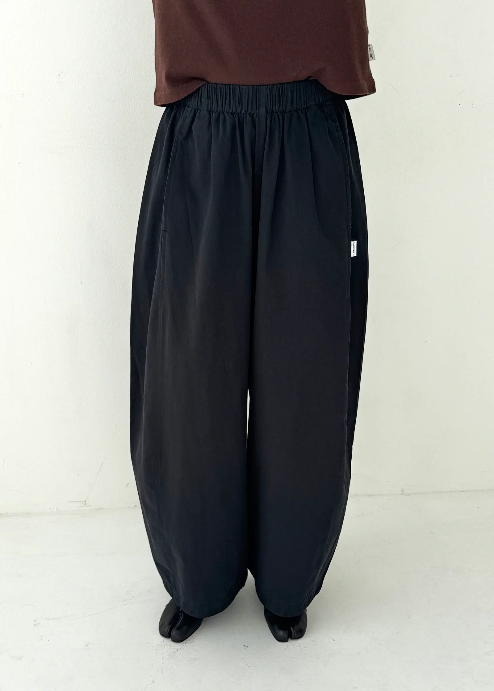 Person wearing black wide-leg pants on a white background
