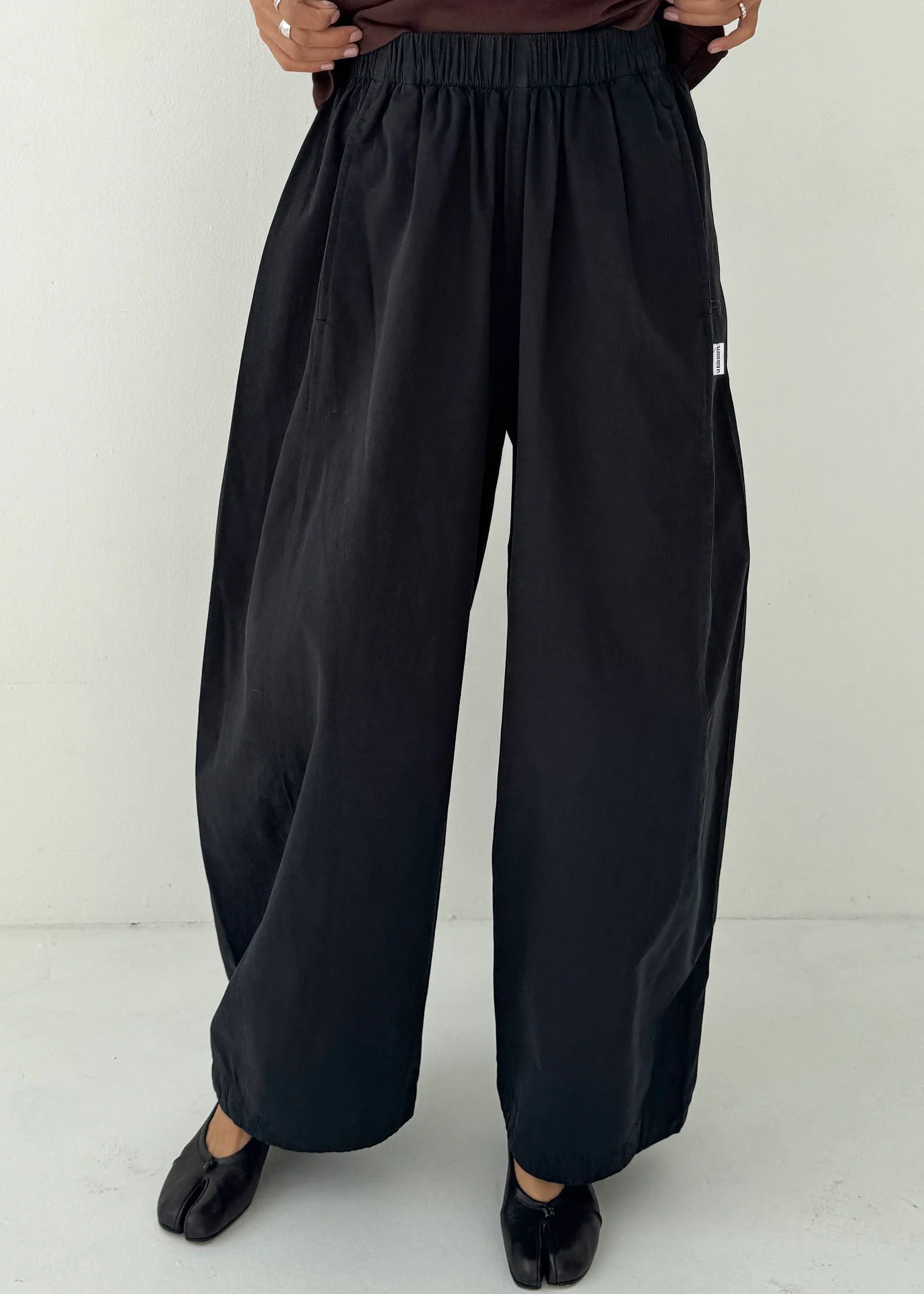 Person wearing black wide-leg pants on a white background