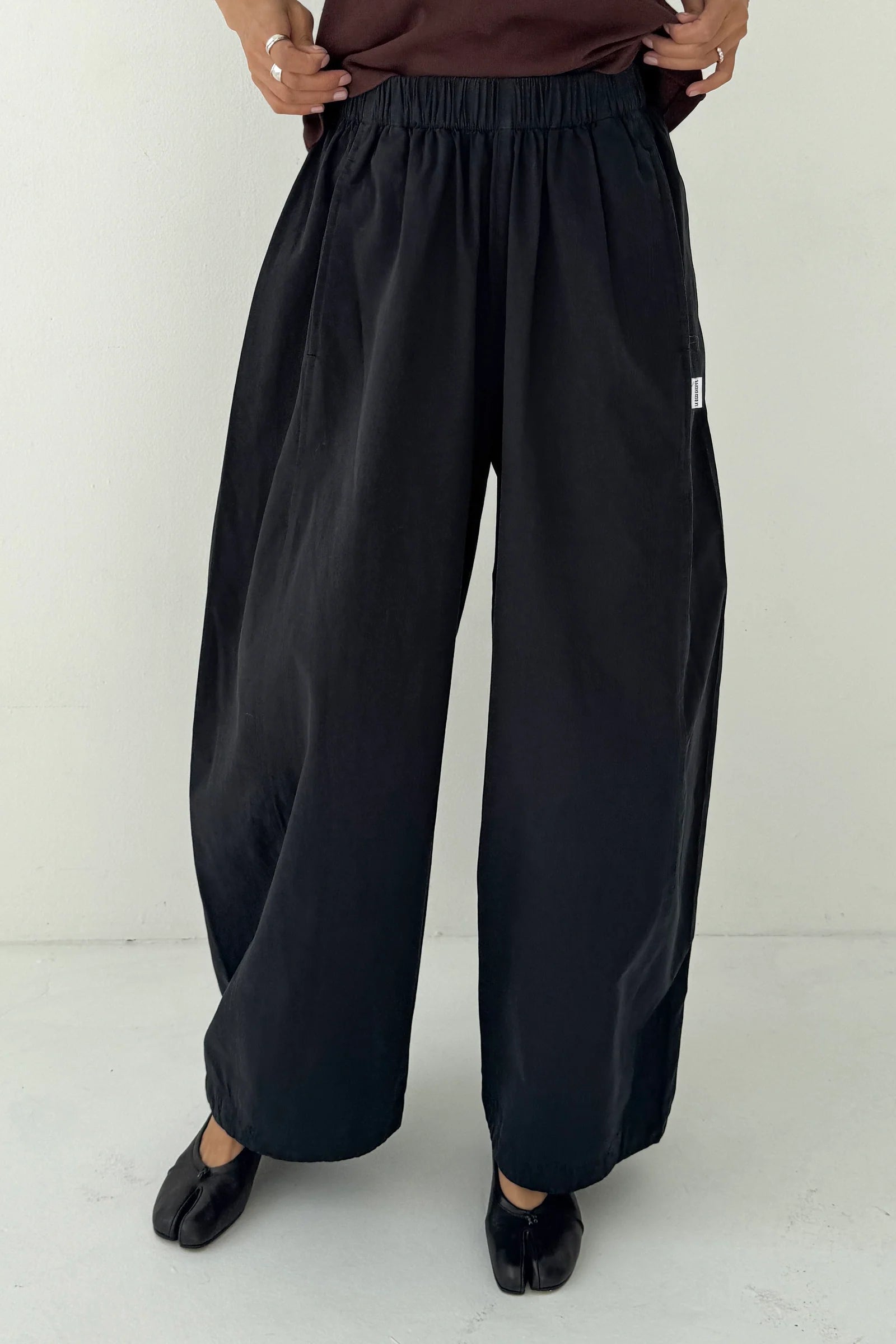 Person wearing black wide-leg pants on a white background