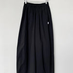 Black skirt hanging on a wooden hanger against a white wall