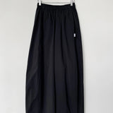 Black skirt hanging on a wooden hanger against a white wall