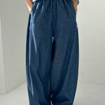 Person wearing blue wide-leg pants and a gray top on a plain background