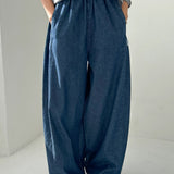 Person wearing blue wide-leg pants and a gray top on a plain background