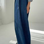 Person wearing blue wide-leg jeans and a gray top on a white background