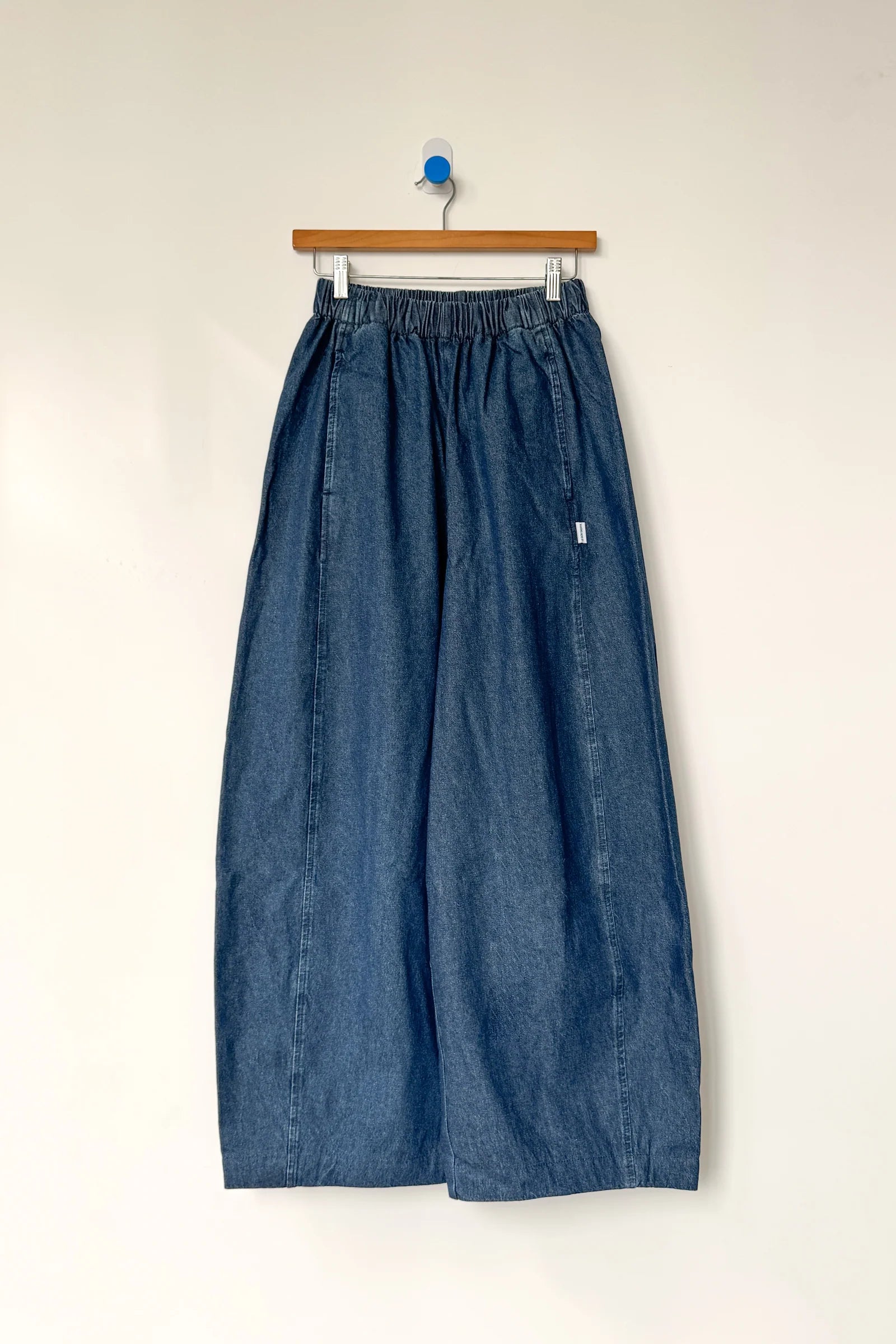 Blue denim skirt on a hanger against a white background