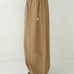 Person wearing beige wide-leg pants and a green top on a white background