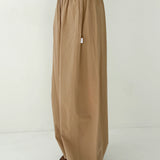 Person wearing beige wide-leg pants and a green top on a white background