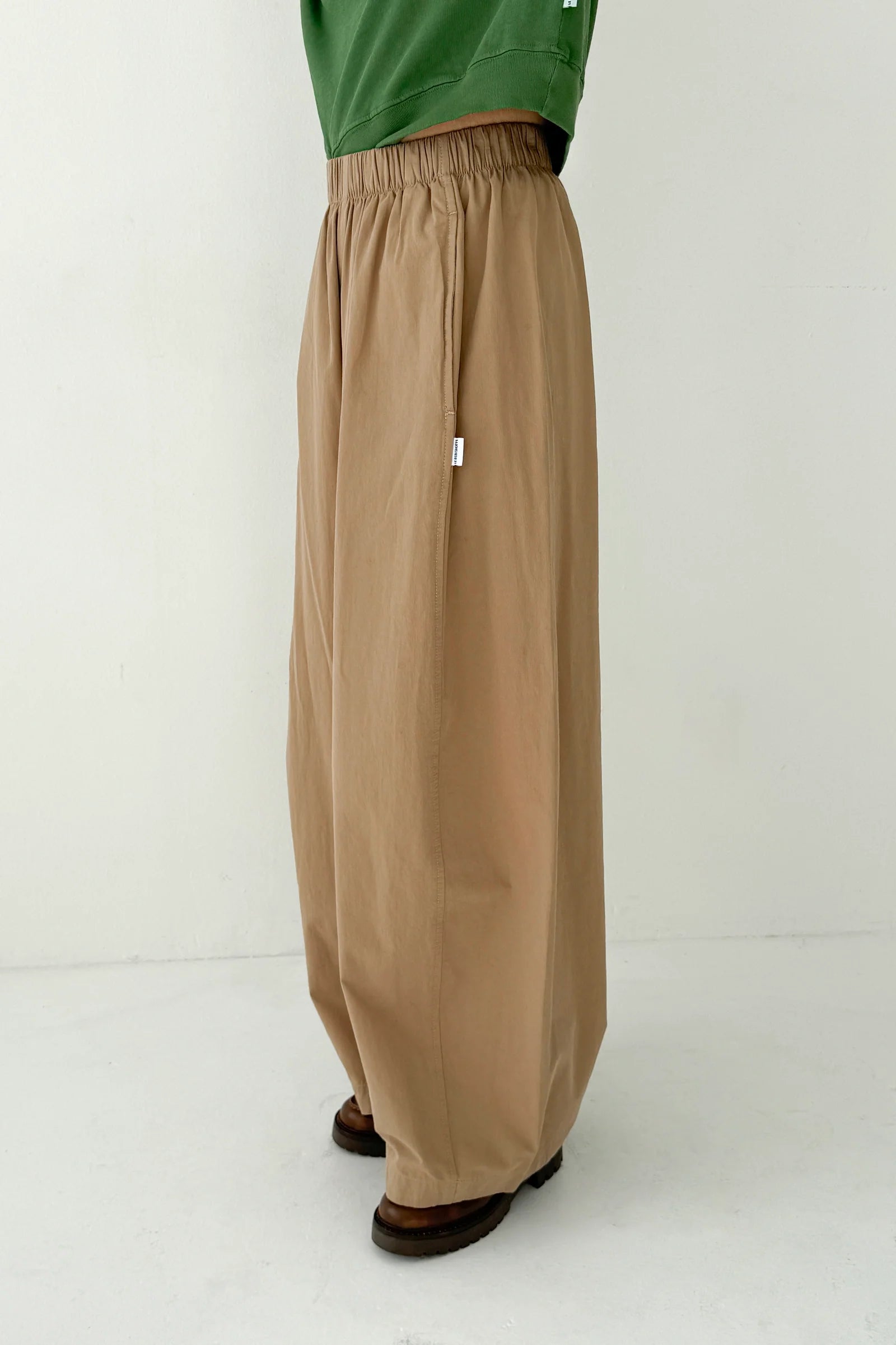 Person wearing beige wide-leg pants and a green top on a white background