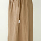 Beige pants with a white tag on a plain background