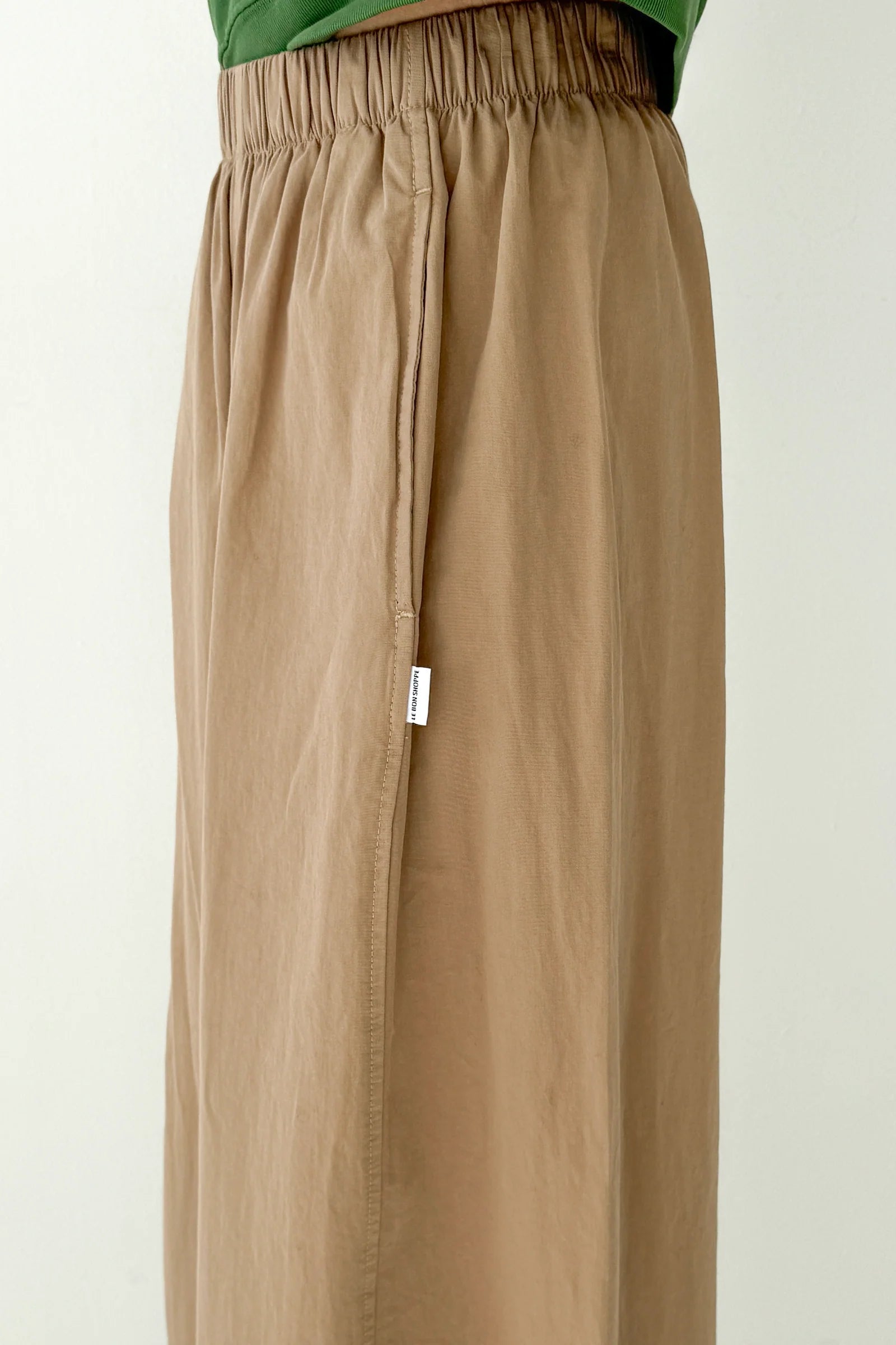 Beige pants with a white tag on a plain background