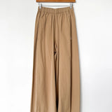 Beige pants hanging on a wooden hanger against a white background