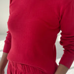 Person wearing a red sweater and pants against a white background