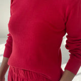 Person wearing a red sweater and pants against a white background
