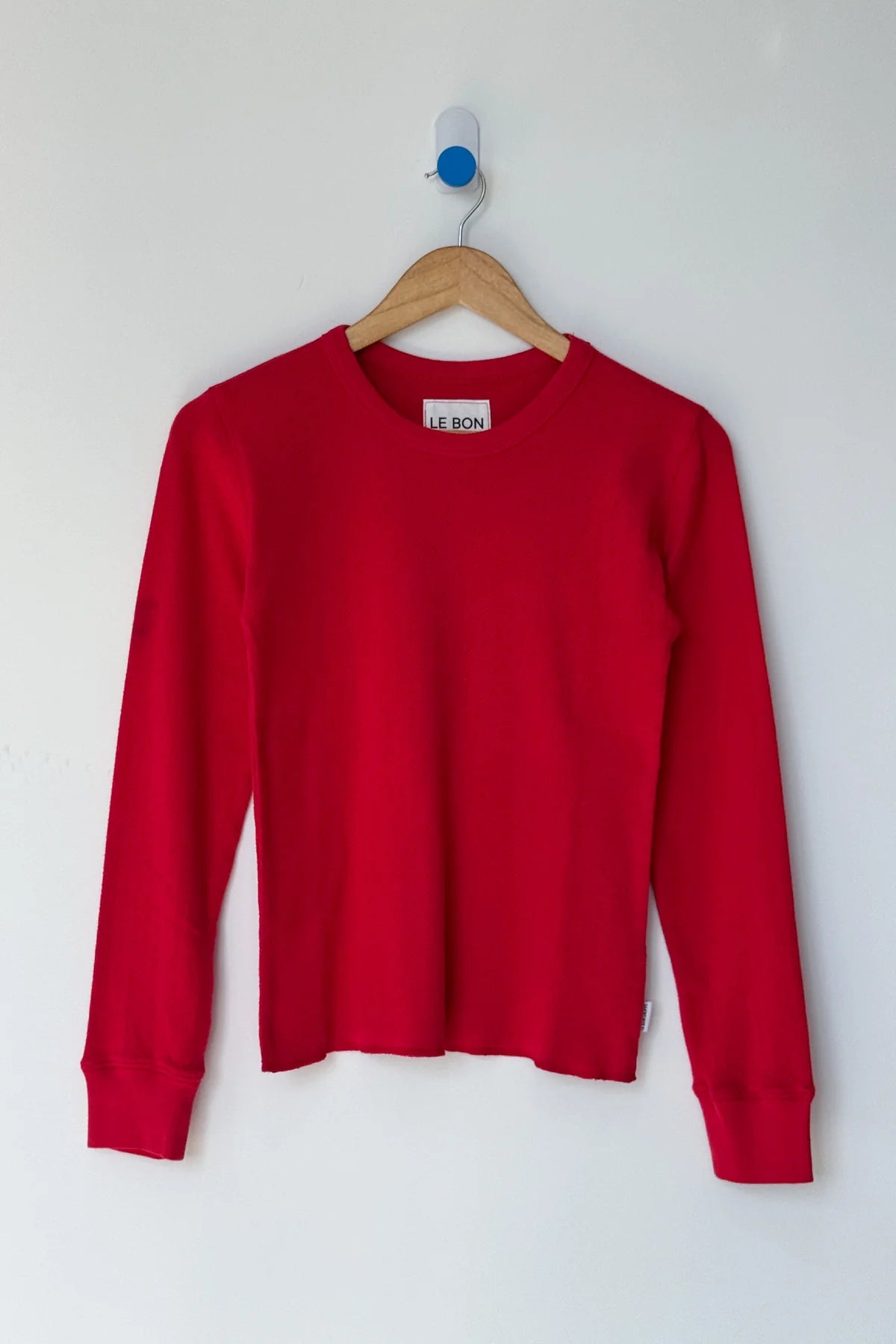 Red sweater on a hanger against a white background