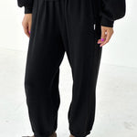 Person wearing black pants and a black top on a white background
