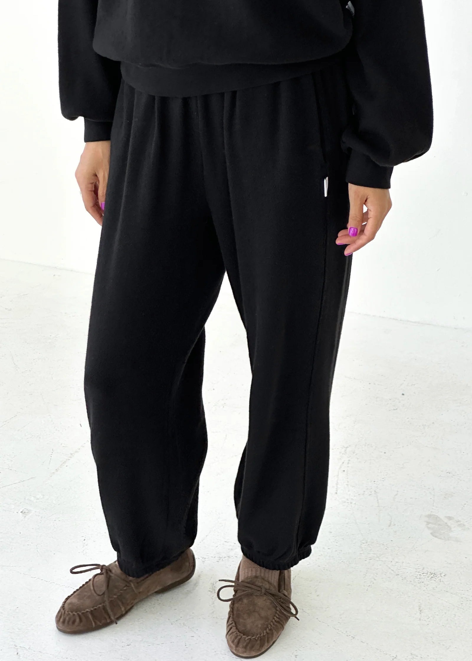 Person wearing black pants and a black top on a white background