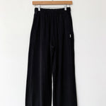 Black pants hanging on a wooden hanger against a white background