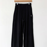 Black pants hanging on a wooden hanger against a white background